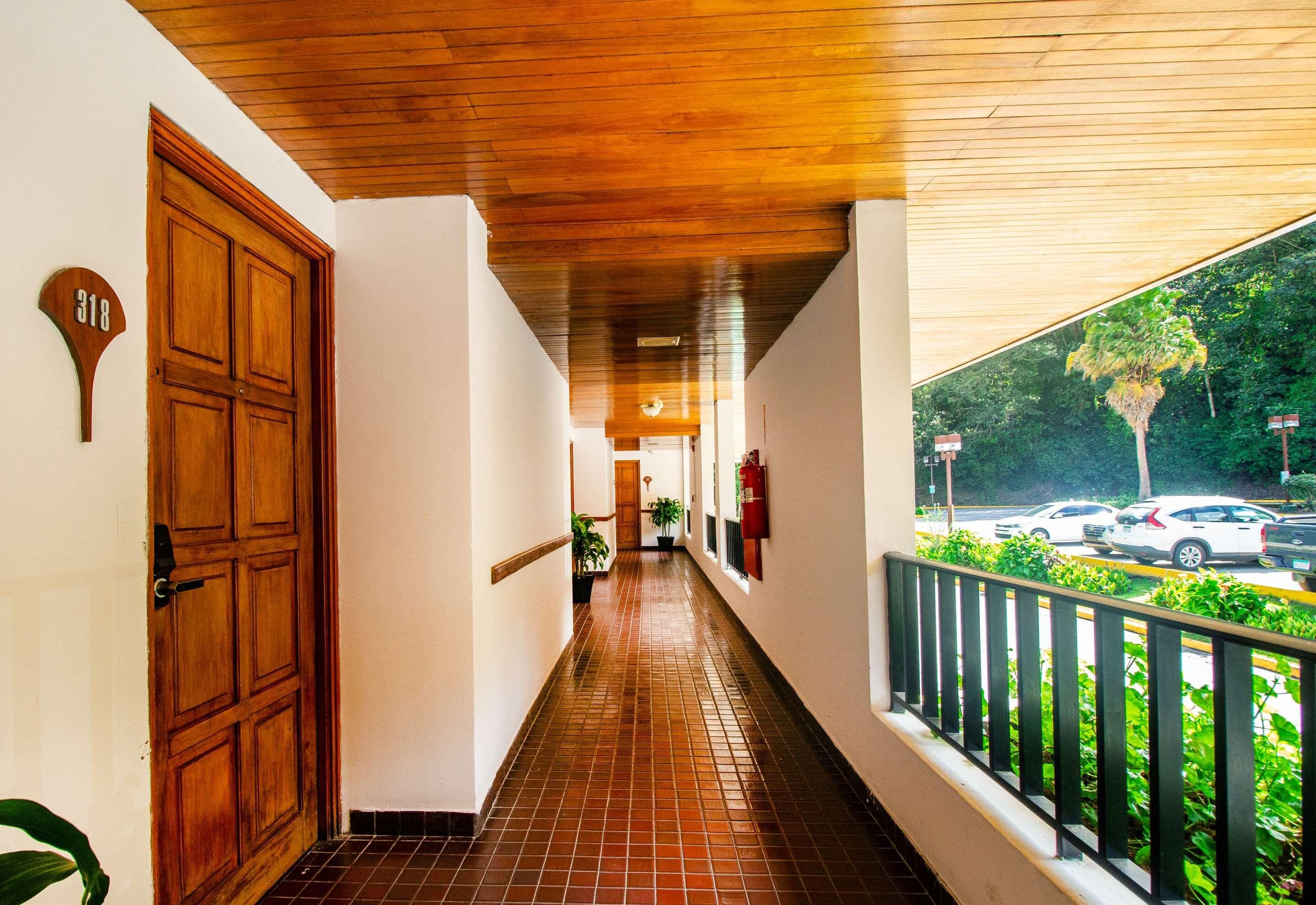 A corridor with a wooden ceiling, a door marked '318', and a balcony with a railing.