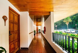 A corridor with a wooden ceiling, a door marked '318', and a balcony with a railing.