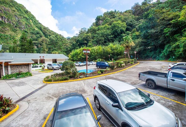 A parking lot with cars, a building with a stone facade, and a mountainous backdrop. - Hotel Bambito By Faranda Boutique, A Member Of Rad (Cerro Punta)