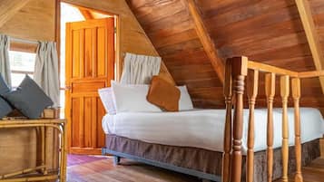 A wooden room with a bed, a door, and a window.