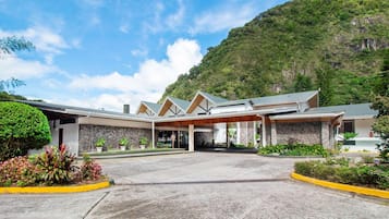 Ein Hotel mit einer Steinauffahrt, einem überdachten Eingang und einer Bergkulisse.