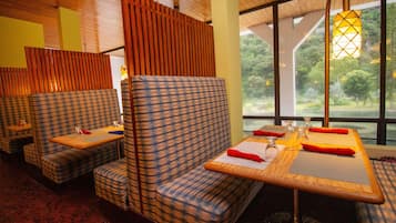 A restaurant with checkered seating, wooden tables, and a view of greenery through large windows.