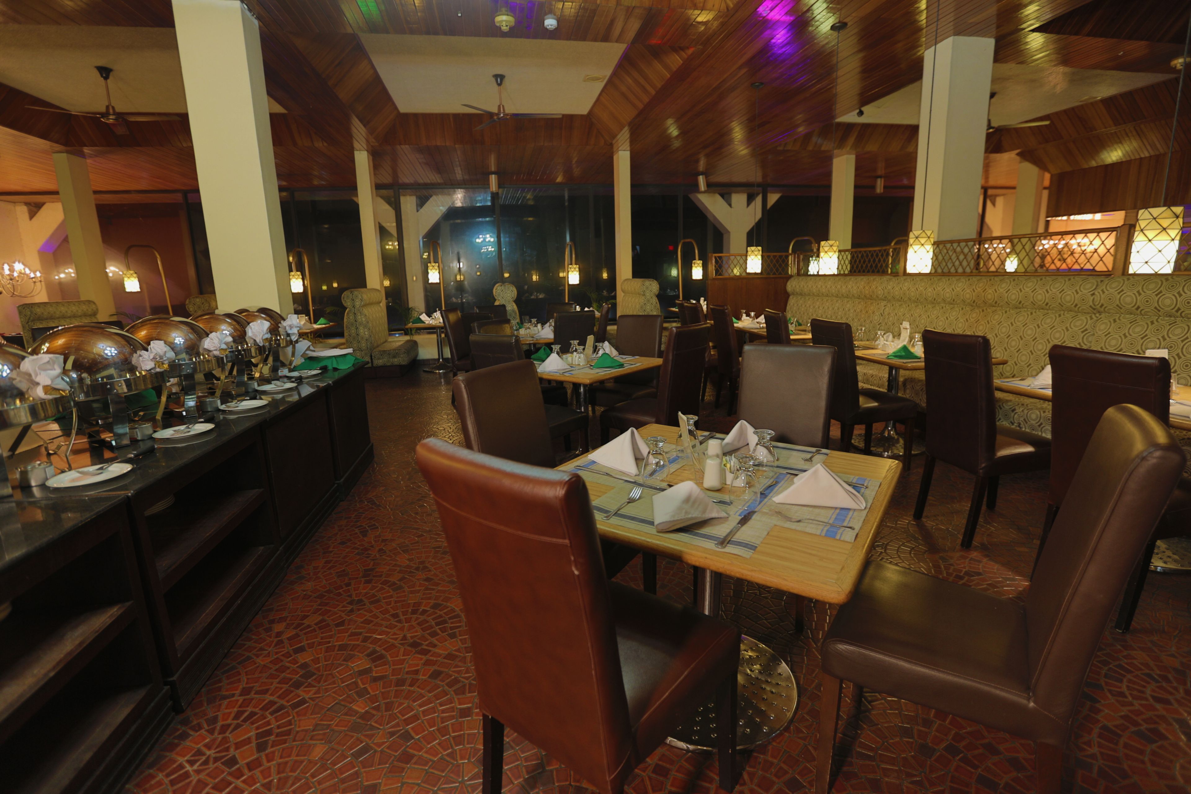 A restaurant with a long counter, multiple tables, and chairs.