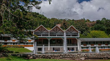 A hotel with a modern architectural design, featuring a prominent balcony and a stone facade.