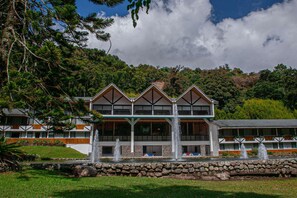 Un hotel con un diseño arquitectónico moderno, que destaca por un balcón prominente y una fachada de piedra.