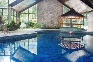 An indoor swimming pool with a stone wall, a gazebo, and a view of greenery outside. - Hotel Bambito By Faranda Boutique, A Member Of Rad (Cerro Punta)