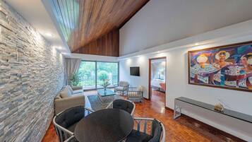 A modern interior with a stone wall, a wooden ceiling, a dining area with a round table, and a large painting.