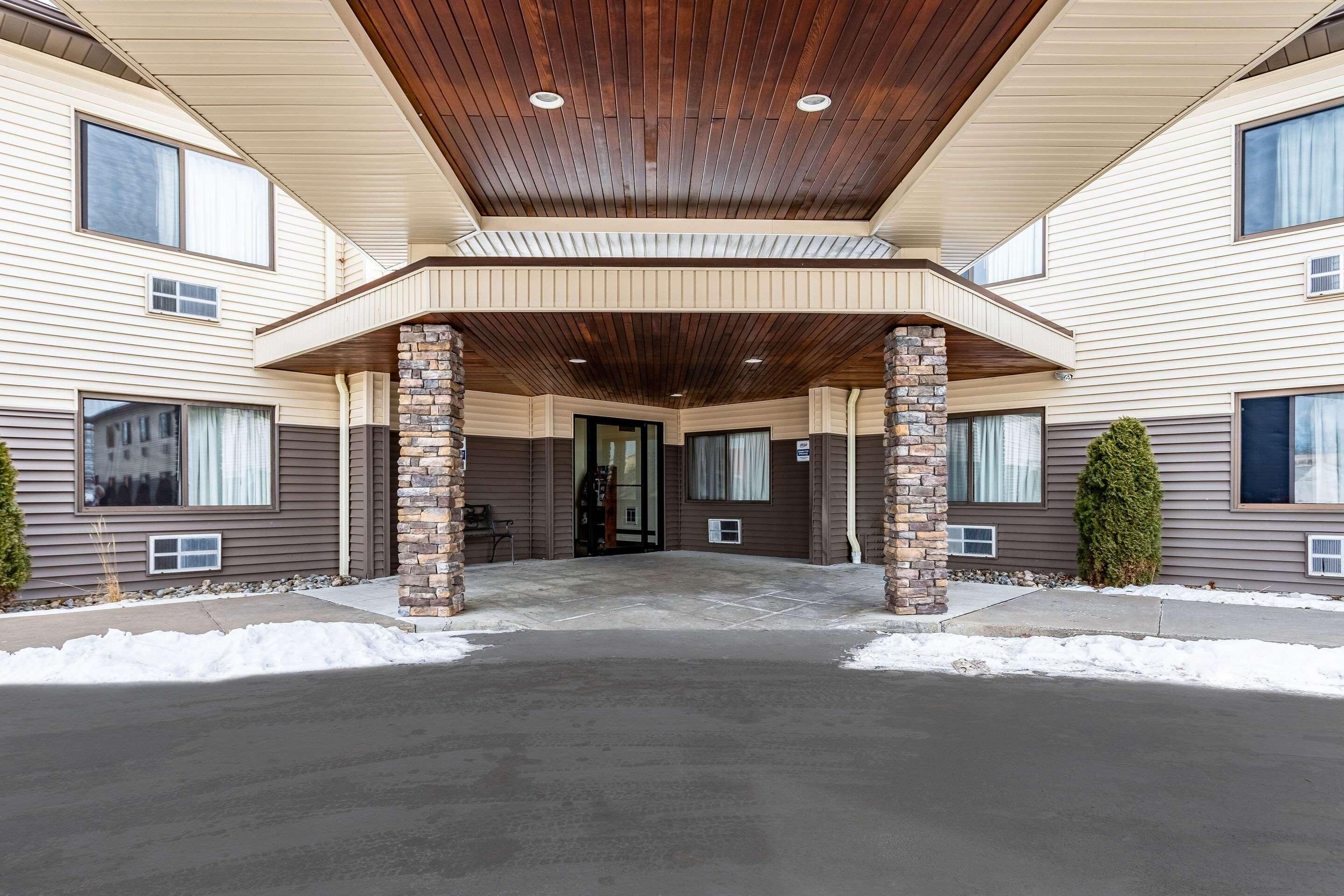 A multi-story building with a covered entrance, stone pillars, and a flat roof.