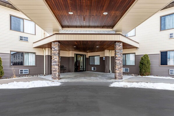 A multi-story building with a covered entrance, stone pillars, and a flat roof.