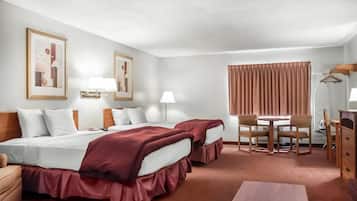 Habitación de hotel con dos camas, un escritorio, sillas, un aparador y dos lámparas de pared.