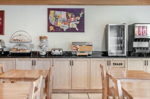 A breakfast bar with a map of the USA, a coffee machine, a pastry display, and a trash bin. - Econo Lodge Ithaca Area (Ithaca)