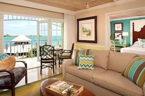 A hotel room with a balcony, a sofa, a dining table with chairs, and a bed. - Ocean Key Resort & Spa (Key West)