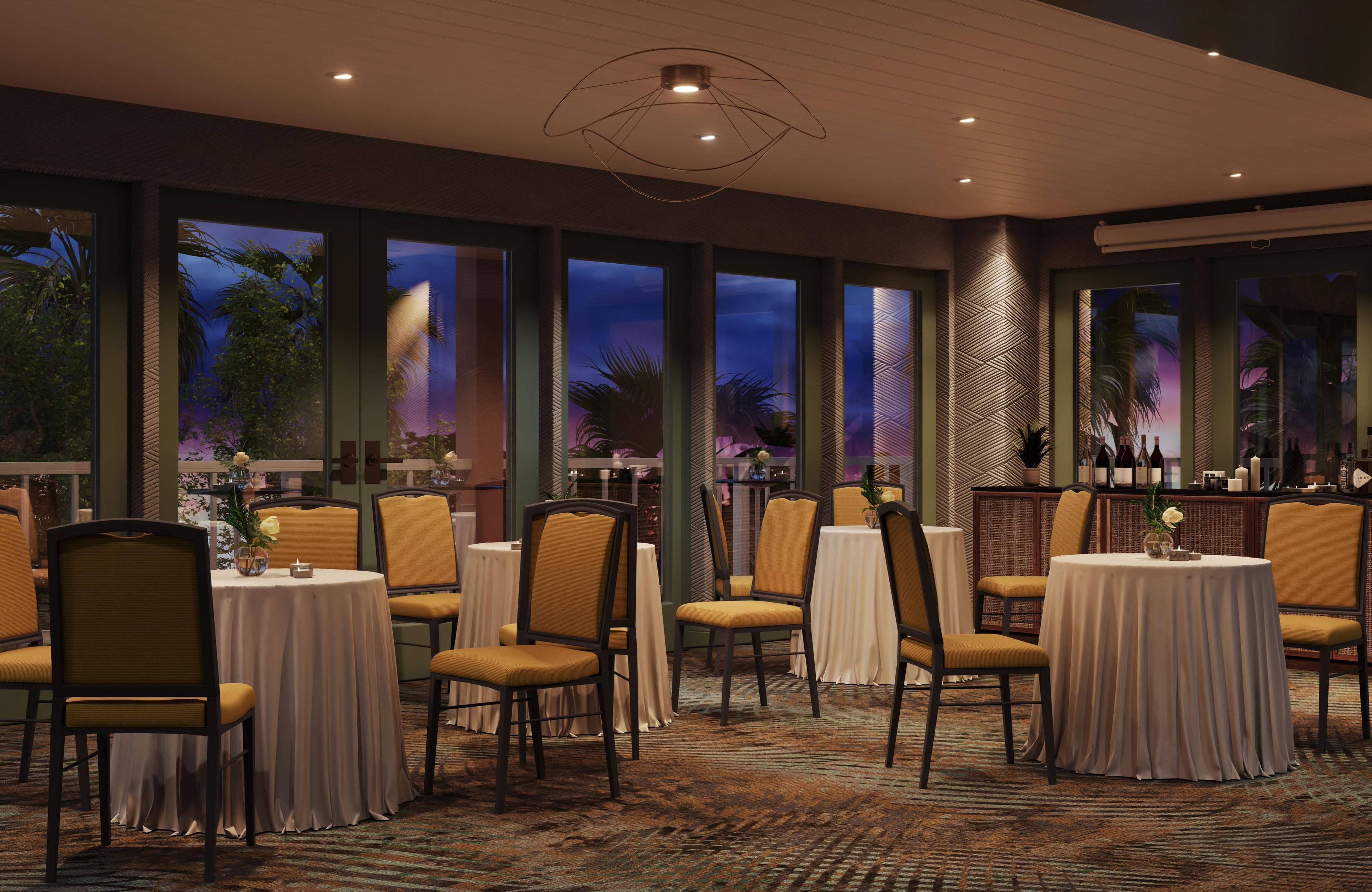 A restaurant with multiple tables and chairs, large windows with a view, and a patterned carpet.
