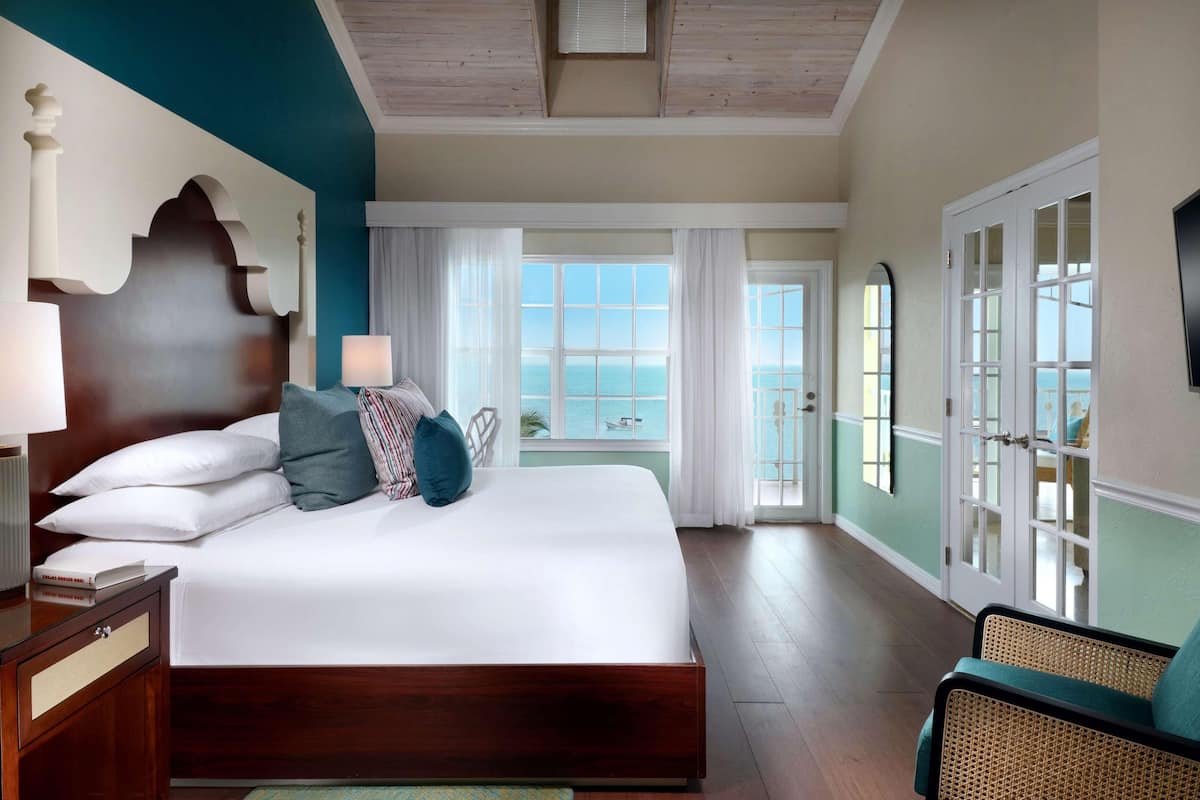 A hotel room with a large bed, a view of the sea, and a balcony.