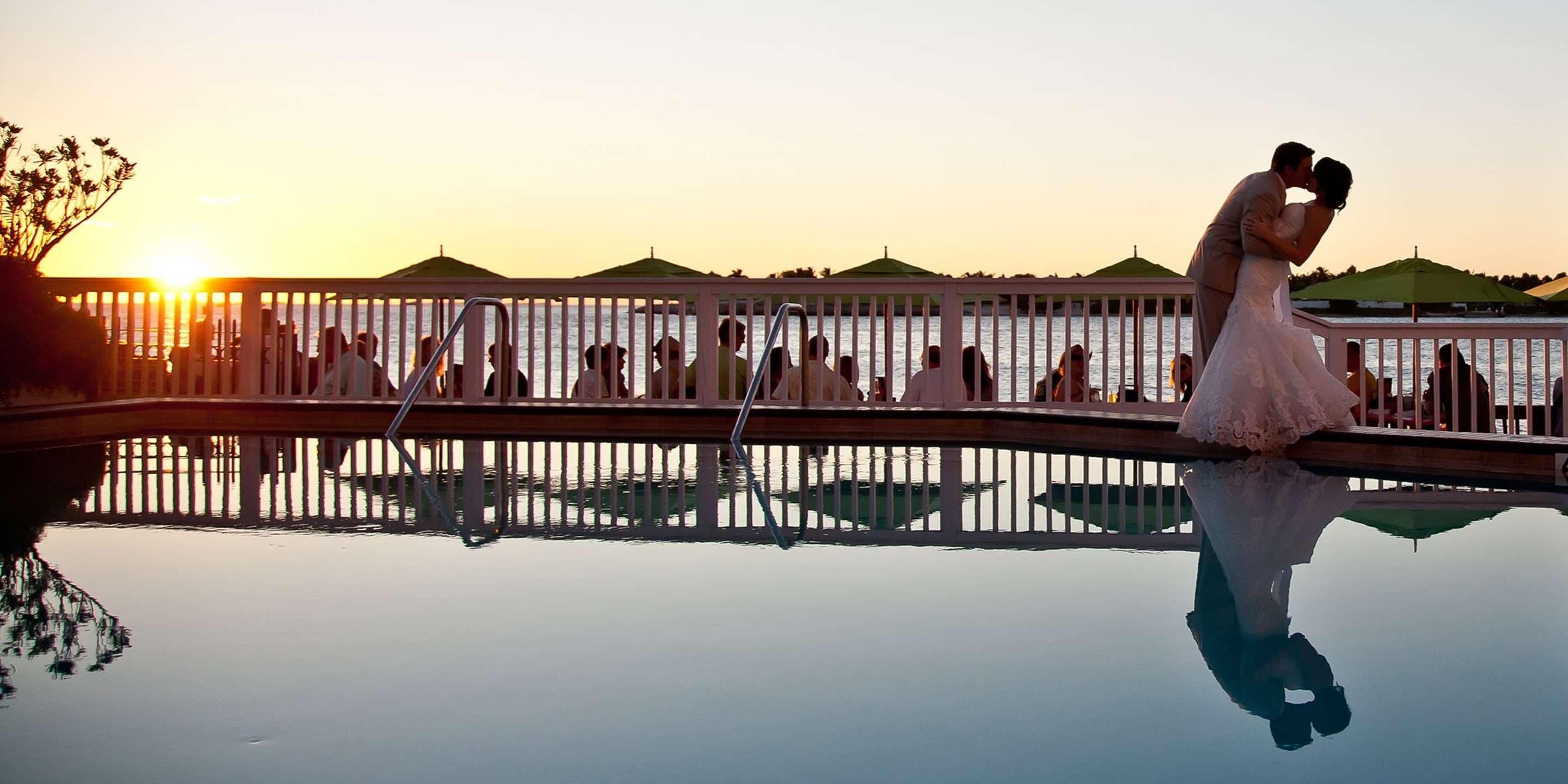 A wedding ceremony at sunset with a reflective pool in the foreground.