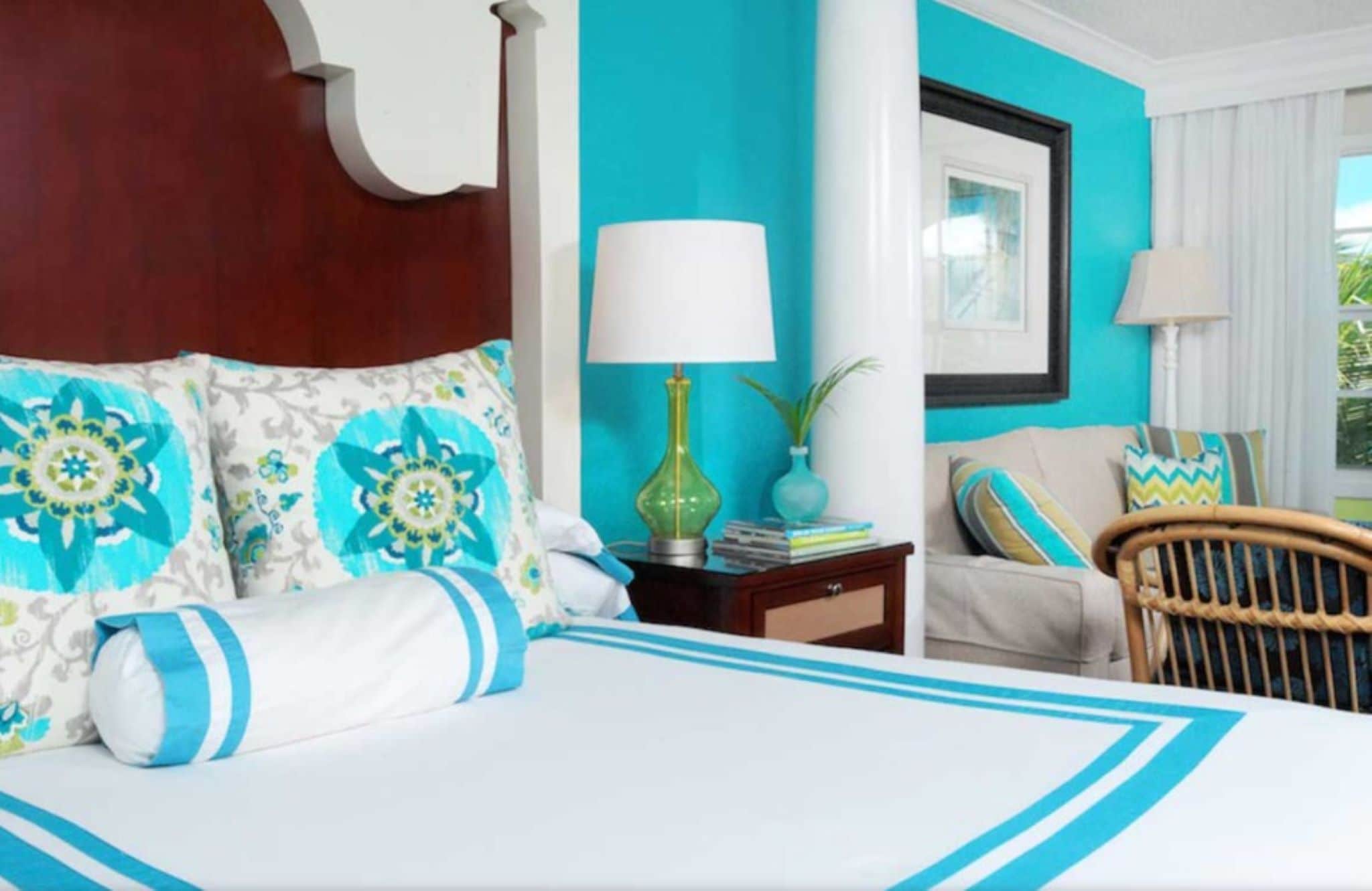 A hotel room with a bed, a nightstand, a lamp, a chair, and a window with curtains.