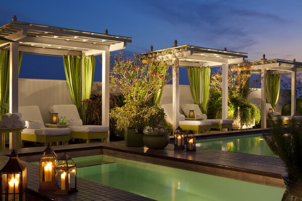 A poolside area with lounge chairs, a pool, and a pergola structure.