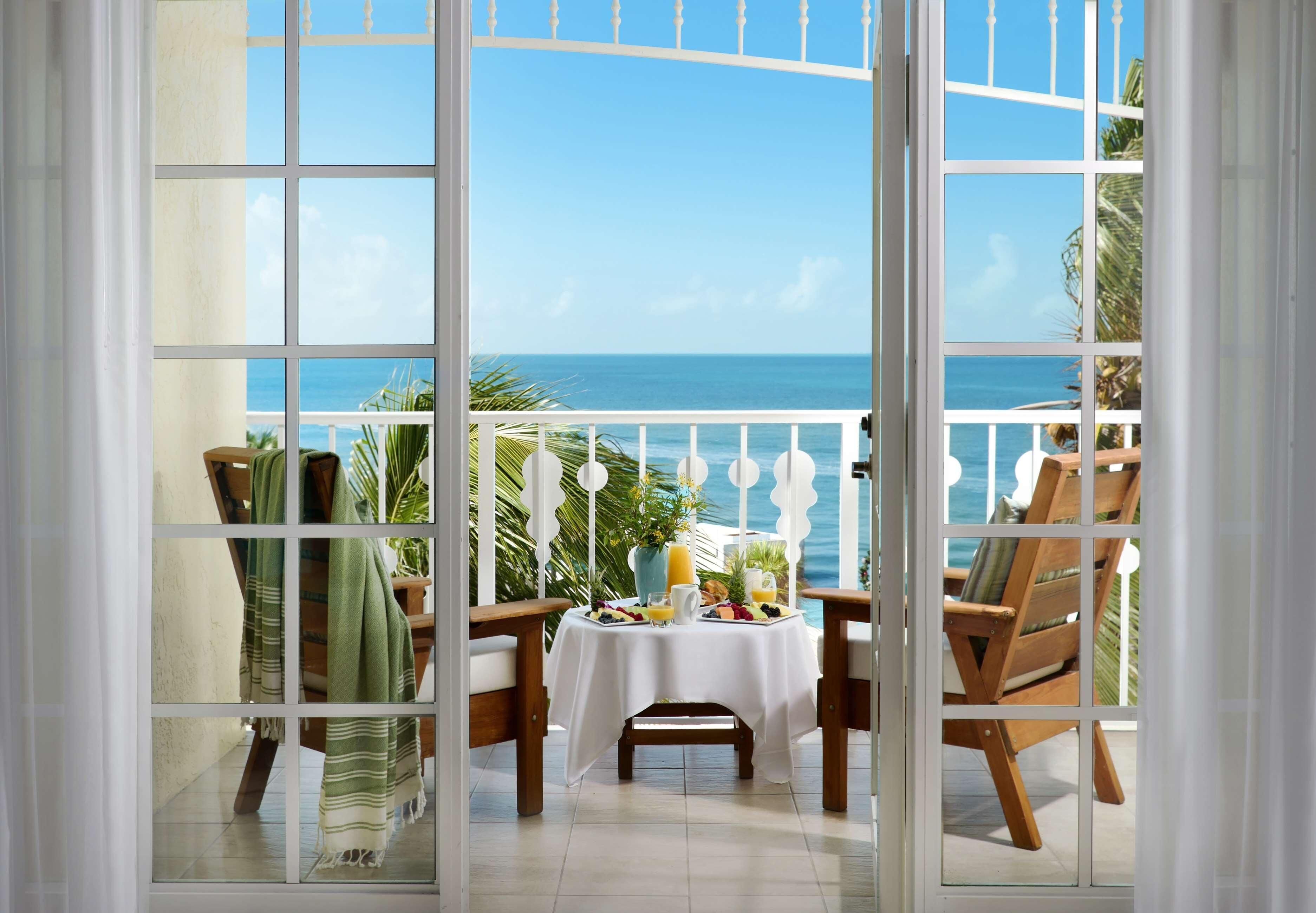 A balcony with a table set for breakfast, overlooking the sea.