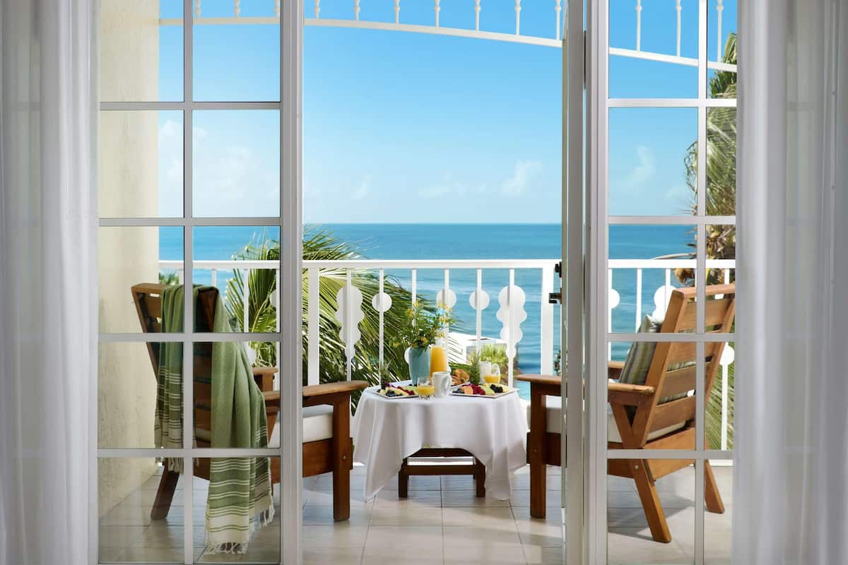 A balcony with a table set for breakfast, overlooking the sea.