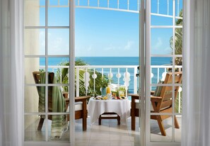 A balcony with a table set for breakfast, overlooking the sea.