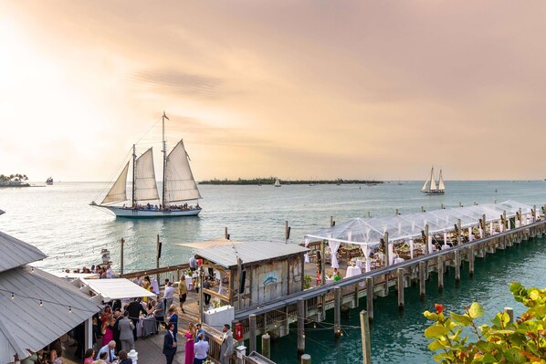 A pier with a row of covered seating areas and a sailboat in the background. - Ocean Key Resort & Spa (Key West)