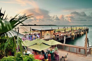 Ein Restaurant am Wasser mit Terrassensitzgelegenheiten, einer Holzsteganlage und Meerblick.