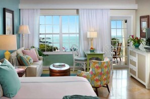 A hotel room with a bed, a desk, a chair, and a view of the sea. - Ocean Key Resort & Spa (Key West)