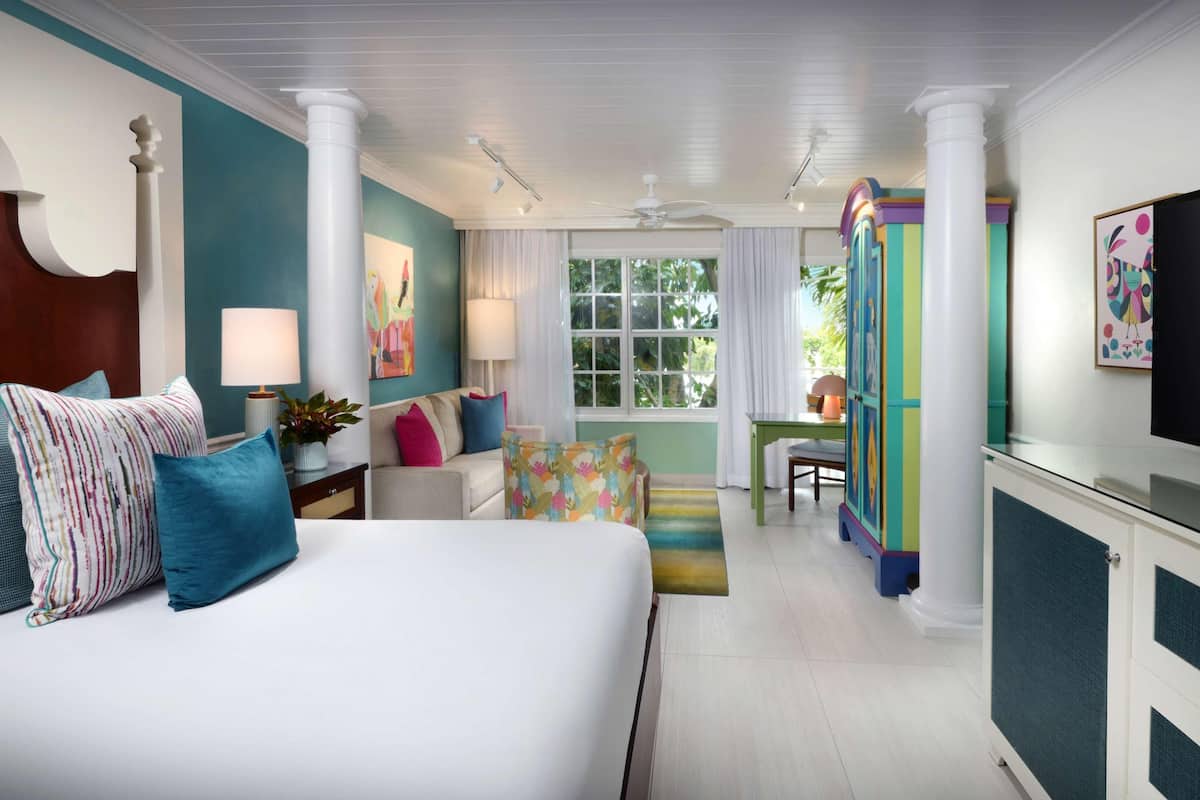 A hotel room with a large bed, a desk, a chair, and a TV.