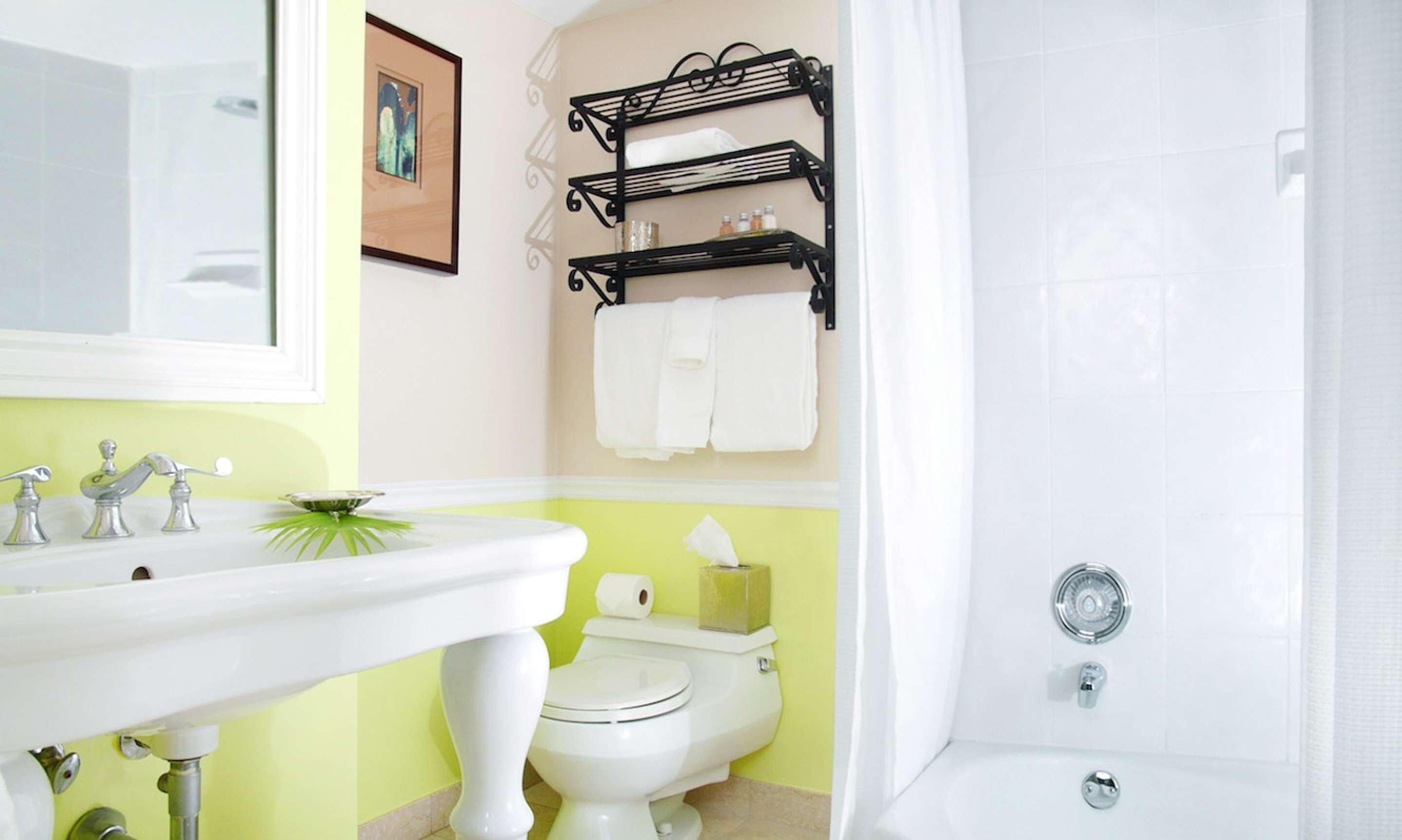 Une salle de bain avec un lavabo blanc, des toilettes et une baignoire. Des serviettes sont suspendues sur un porte-serviettes et un tableau encadré est accroché au mur.