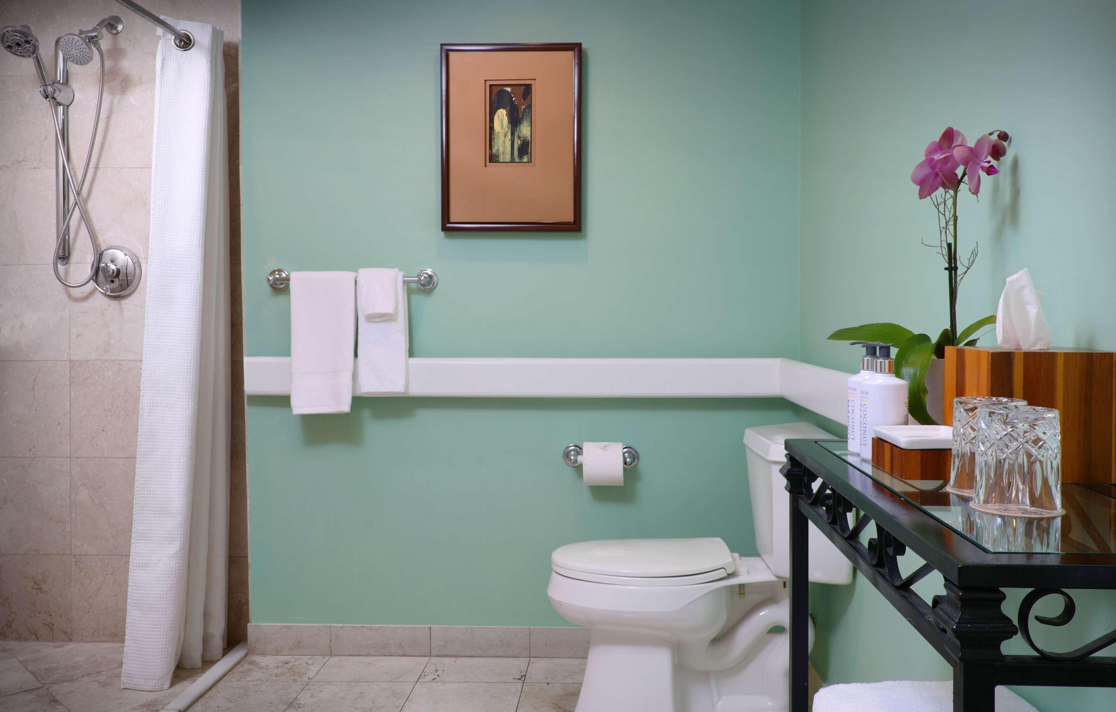 Un baño con ducha, inodoro y un cuadro en la pared.
