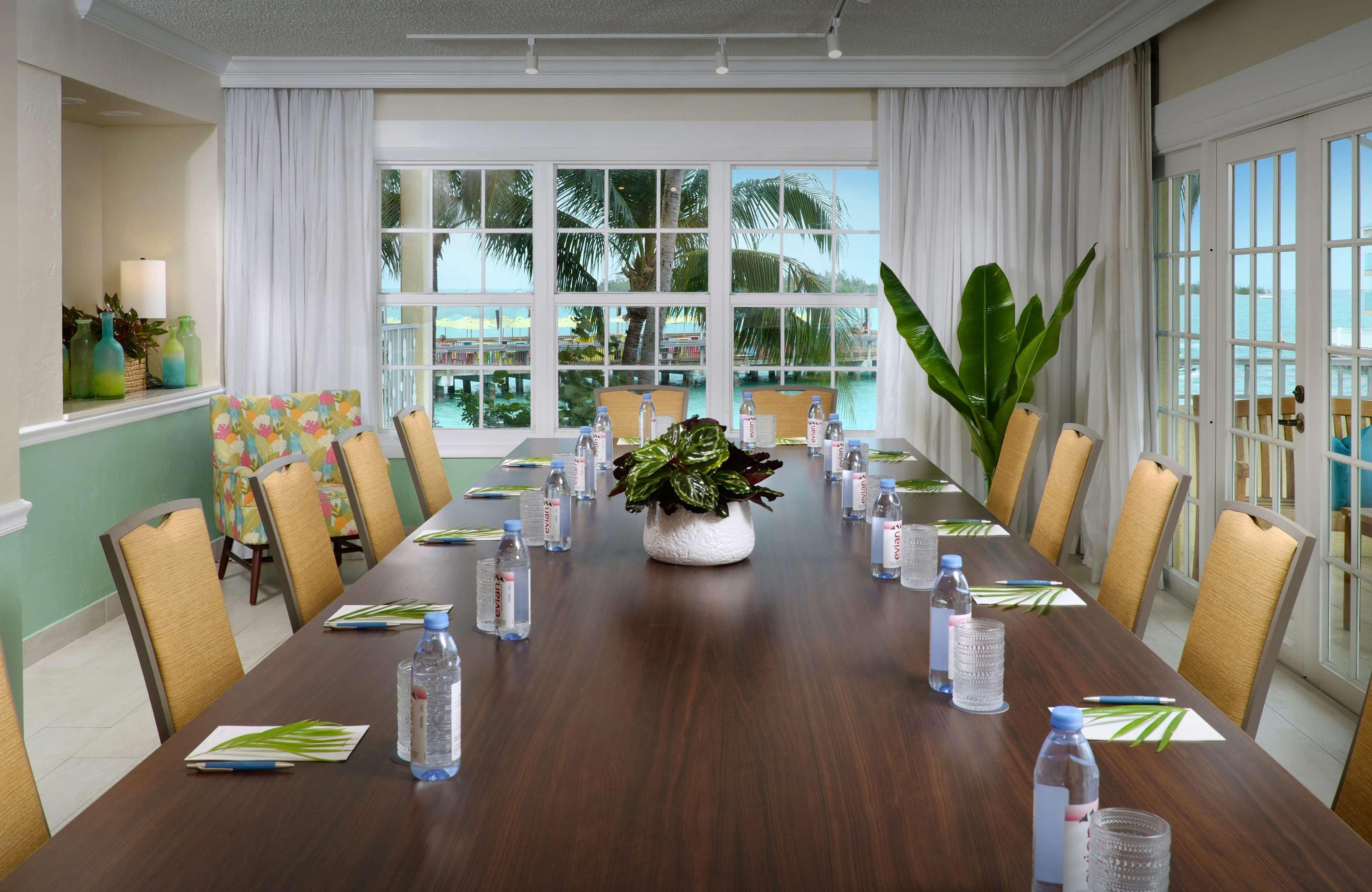 A conference room with a long table, chairs, water bottles, and a potted plant.