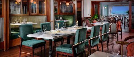 A restaurant with wooden flooring, green upholstered booths, and tables set for dining.