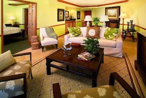 A hotel room with a bed, a sitting area with a sofa and armchairs, a coffee table, and a dining table. - Ocean Key Resort & Spa (Key West)