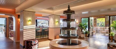 A lobby with a central water feature, seating areas, and a view of the outdoors.