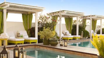 Un espace aménagé au bord de la piscine, avec des chaises longues, une piscine et des plantes en pot.
