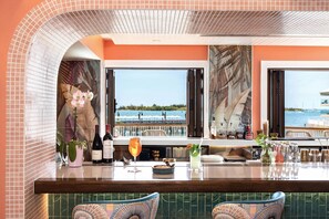 A bar area with a view of the sea, a wine bottle, and a cocktail glass. - Ocean Key Resort & Spa (Key West)