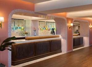 A reception area with a wooden reception desk, a tiled wall, and hanging glass bottles.