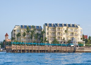 A waterfront hotel with multiple balconies, a wooden pier, and a small tower structure.