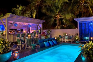 A poolside area with a bar, seating, and palm trees. - Ocean Key Resort & Spa (Key West)