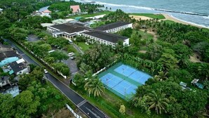 An aerial view of a coastal area with a tennis court, buildings, and a beach.