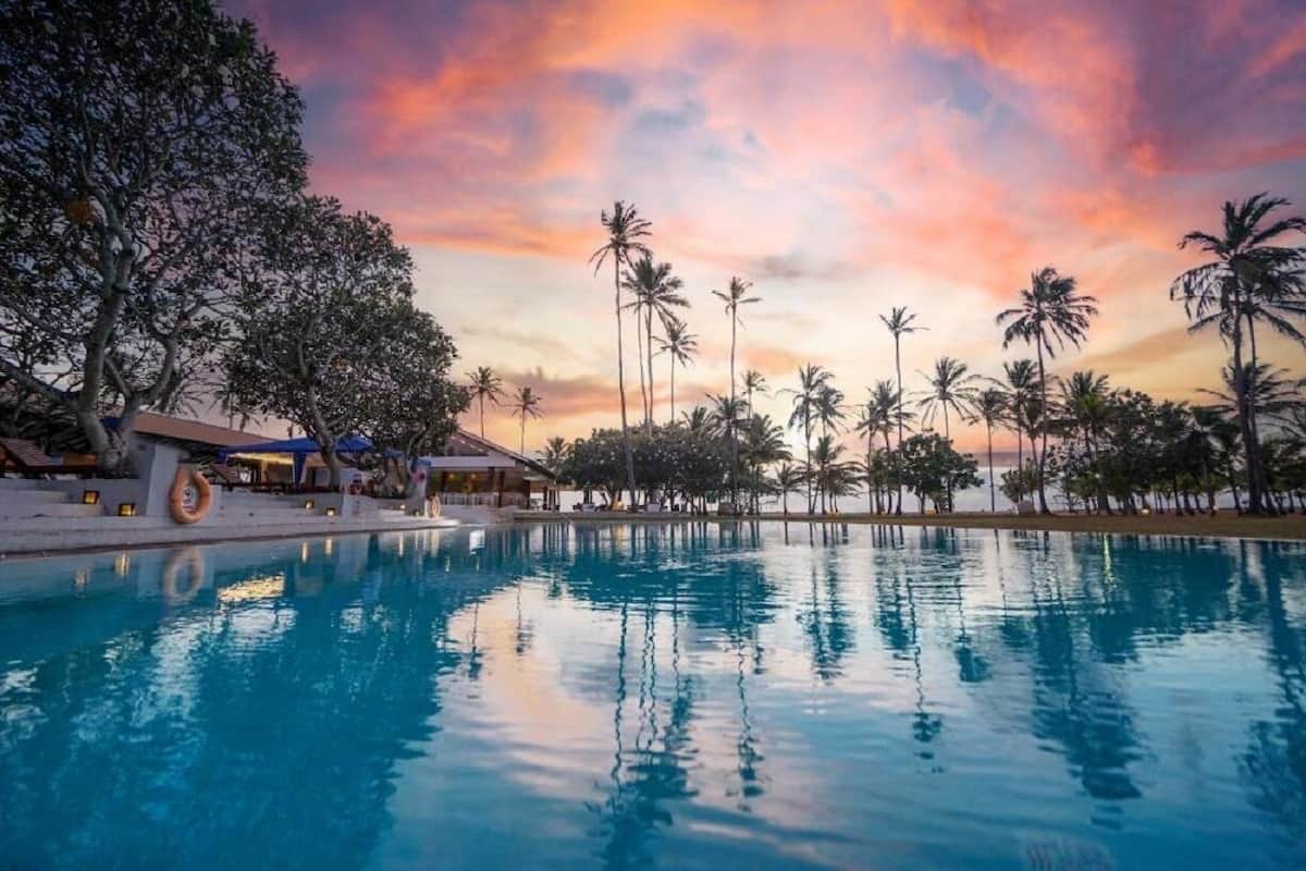 Una piscina con palmeras y un edificio al fondo.