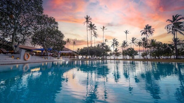 Una piscina con palmeras y un edificio al fondo.