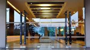 Un moderno vestíbulo de hotel con mostrador de recepción, zona de estar y un amplio ventanal con vistas al exterior.