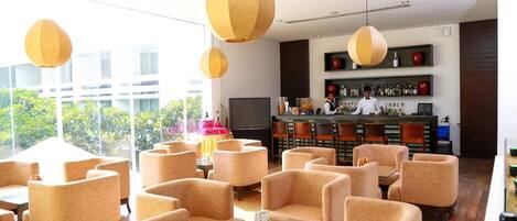 A modern bar area with seating and a bartender.
