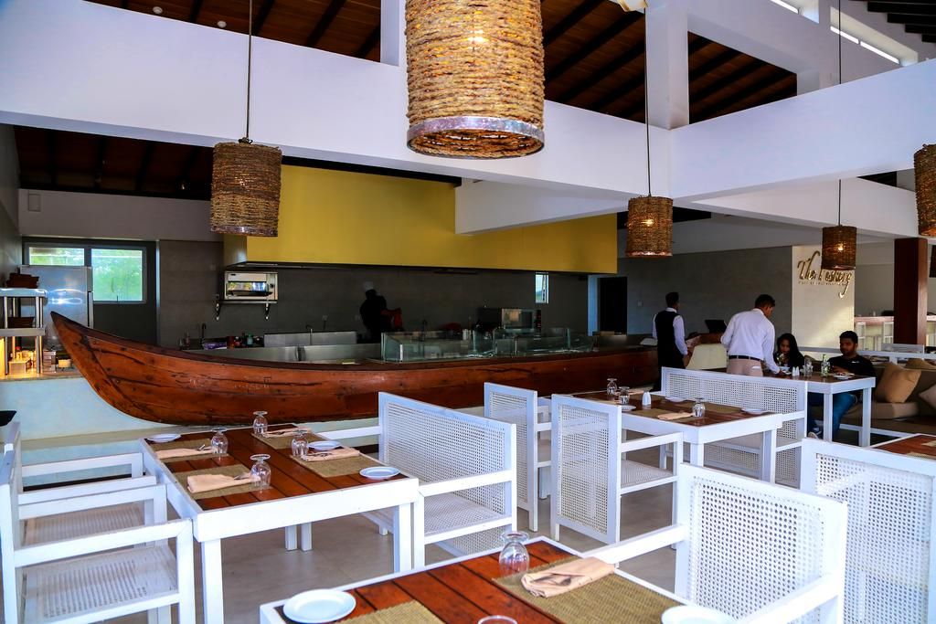 A restaurant with white furniture and a wooden boat-shaped counter.