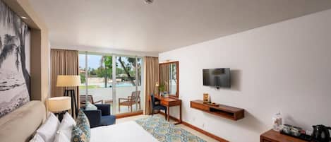 A hotel room with a bed, a desk, a TV, and a view of the outdoors.