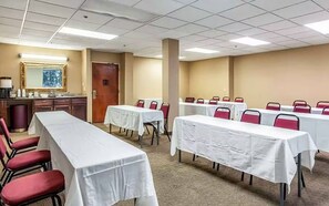 A conference room with tables and chairs, a kitchenette, and a door. - Motel 6 Conway (Conway)