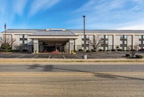 A building with a flat roof, a central entrance, and a parking lot. - Motel 6 Conway (Conway)