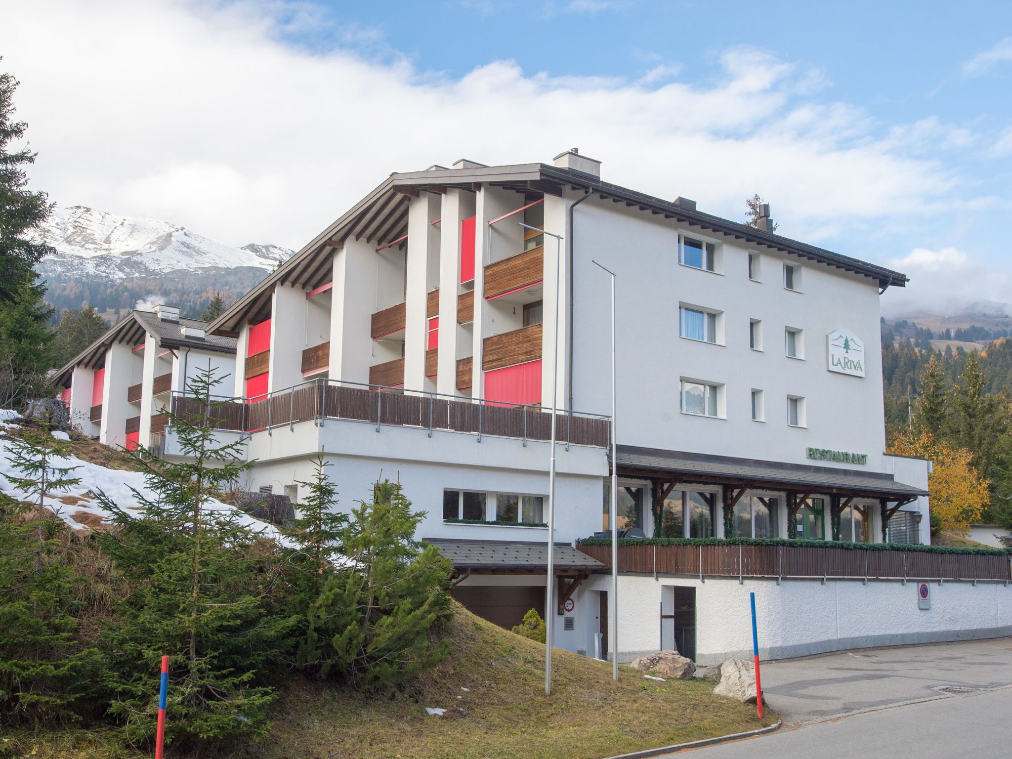 Ein mehrstöckiges Hotel mit Restaurant im Erdgeschoss, vor einer Bergkulisse gelegen.