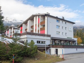 Ein mehrstöckiges Hotel mit Restaurant im Erdgeschoss, vor einer Bergkulisse gelegen.
